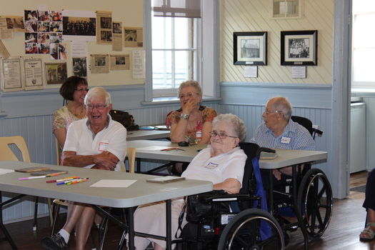 four seniors laughing sitting at desks